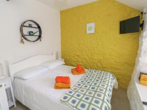 sypialnia z białym łóżkiem z pomarańczowymi poduszkami w obiekcie Primrose Cottage w mieście Tenby