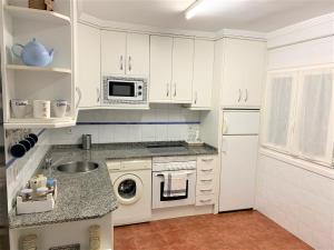 a white kitchen with a sink and a microwave at Apartamento Parque - Playa San Lorenzo in Gijón