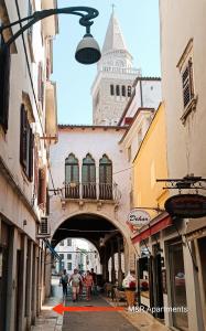 a street with a building with a clock tower at M&R Apartments I in Koper