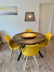 einem Esstisch mit gelben Stühlen und einem Teller Essen darauf in der Unterkunft Apartment auf zwei Ebenen mit Aussicht ins Grüne in Stuttgart
