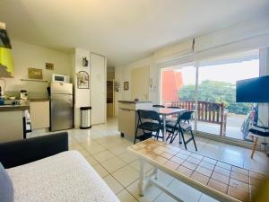 a kitchen and a living room with a table and chairs at ''Croisette'' Appartement rez de jardin accès direct plage ! in Sète