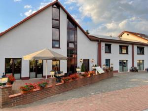 a large white building with a patio and an umbrella at Freigeist • Pension & Brasserie in Witzin