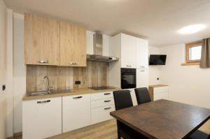 una cucina con armadi bianchi e tavolo in legno di Appartamento Fede a Livigno