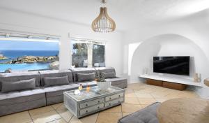 a living room with a couch and a tv at Paraga Villa1 "7min WALK TO BEACH" by Calypso Sunset Villas in Mikonos