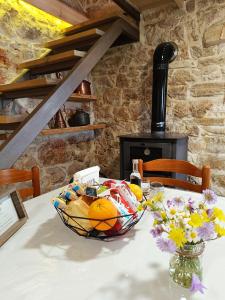 einen Tisch mit einem Korb mit Orangen und Blumen darauf in der Unterkunft Agios Ioannis Stone Cottage with Private Heated Pool & Hydro-massage in Áyios Ioánnis