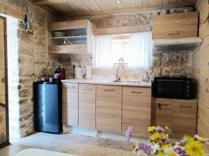 eine Küche mit Holzschränken, einer Spüle und einer Mikrowelle in der Unterkunft Agios Ioannis Stone Cottage with Private Heated Pool & Hydro-massage in Áyios Ioánnis