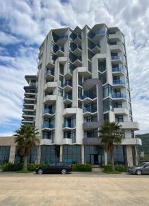 a large apartment building with palm trees in front of it at Pano Hotel in Gonio