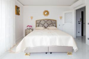 a white bedroom with a large bed with a gold headboard at La Perle Bleue - Central - Vue Mer - Wifi in Roquebrune-Cap-Martin