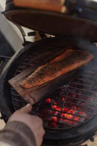 a person is cooking a piece of bread on a grill at Yggdrasil Igloo Skåne in Höör