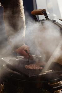 une personne prépare des hamburgers sur un grill dans l'établissement Yggdrasil Igloo Skåne, à Höör