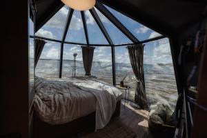 Cama en habitación con ventana grande en Yggdrasil Igloo Skåne, en Höör