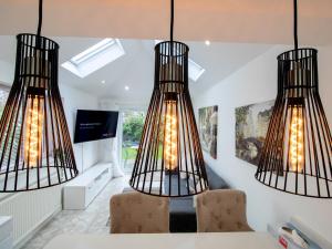 a dining room with three lights hanging from the ceiling at Pass the Keys Modern Coastal Cottage in North Shields