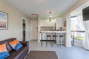 a living room with a couch and a kitchen at Rooftop Pool | Balcony with Sea View #CA45 in Florianópolis