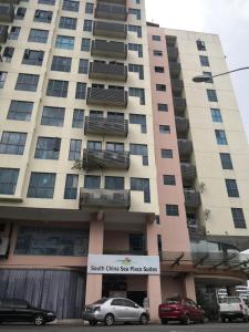 a tall building with cars parked in front of it at Stay In Kay Kay Hotel Suite at South China Sea Place Suite in Kota Kinabalu