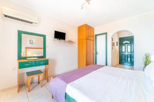 a bedroom with a bed and a desk and a television at Spyridoula Studio 12 in Paleokastritsa