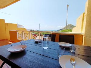 una mesa de madera con platos y vasos en el balcón en Parque Marino 5206 - Resort Choice, en Cabo de Palos