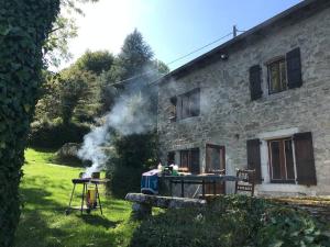 a grill in front of a house with smoke at Maison en pierre dans le Sidobre in Le Bez