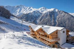 a lodge in the snow with mountains in the background at La Cour aux Ecureuils in Peisey-Nancroix