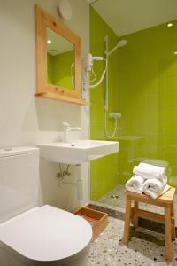 een badkamer met een wastafel, een toilet en groene tegels bij Gintarautojai in Palanga