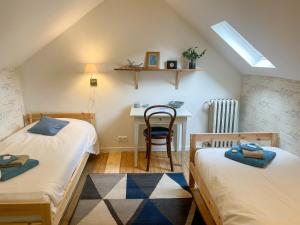 a attic bedroom with two beds and a desk at La Basse Cour in Tanlay