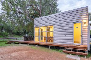 a tiny house with yellow doors and a wooden deck at Whatmans Beach House - on the water's edge in Dunsborough