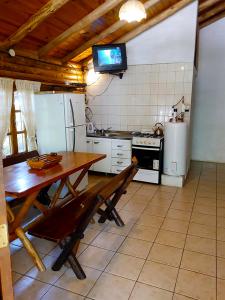 a kitchen with a wooden table and a refrigerator at Cabañas Troncos Del Salto in Potrerillos