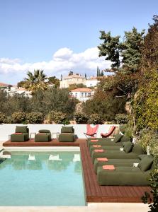 a swimming pool with chaises and chairs next to a swimming pool at Yayaki Spetses in Spetses