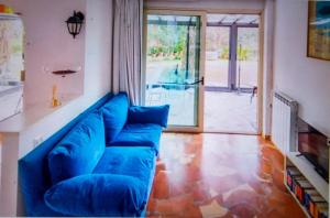 - un canapé bleu dans le salon avec une porte en verre dans l'établissement Casa Dei Leoni, luminoso open space immerso nel verde, à Rome
