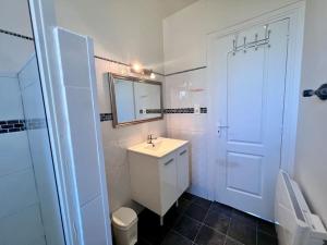 La salle de bains blanche est pourvue d'un lavabo et d'un miroir. dans l'établissement Maison des Papillons - Jolie Maison - Proche Centre Brive, à Brive-la-Gaillarde