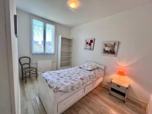 een slaapkamer met een bed en een tafel met een lamp bij Maison des Papillons - Jolie Maison - Proche Centre Brive in Brive-la-Gaillarde