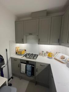 a kitchen with white cabinets and a stove top oven at Inviting & Spacious 3BD Flat - Shadwell in London