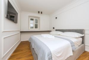 a white bedroom with a large bed and a television at Palace Heritage Apartments in Makarska