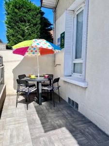 een tafel met een kleurrijke parasol op een patio bij Maison des Papillons - Jolie Maison - Proche Centre Brive in Brive-la-Gaillarde
