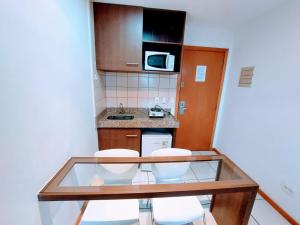 a small kitchen with two chairs and a glass table at Flat Hotel Nobile A18 in Brasilia