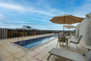a swimming pool with a table and umbrella on a roof at Flat Hotel Nobile A18 in Brasilia