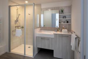 La salle de bains est pourvue d'une douche, d'un lavabo et d'un miroir. dans l'établissement Résidence Services Seniors DOMITYS - LA BELLE EPOQUE, à Dinard