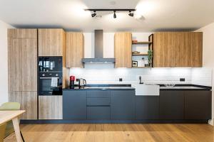 a kitchen with blue counters and wooden cabinets at Spacious Modern Hackney Flat in London