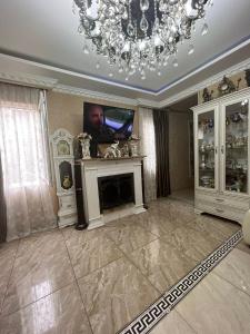 a living room with a fireplace and a chandelier at Guest House Nice in Tbilisi City