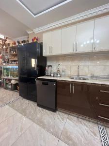 a kitchen with a sink and a black refrigerator at Guest House Nice in Tbilisi City