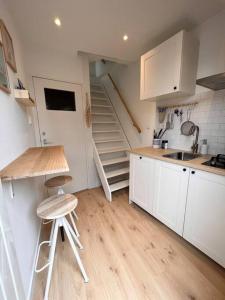 una cocina con armarios blancos, lavamanos y escaleras en Little Loft, Summerhouse near the beach, en Noordwijk aan Zee