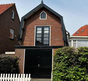 una casa de ladrillo marrón con garaje negro en Little Loft, Summerhouse near the beach en Noordwijk aan Zee