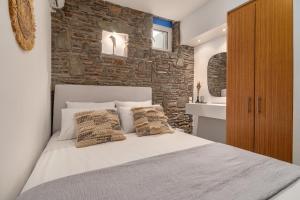 a bedroom with a white bed and a stone wall at Arel luxury house in Kithnos