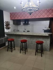 una cocina con 3 taburetes rojos y una barra en House 11 en Ibadán