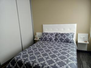 a bedroom with a bed with a black and white comforter at O Abeiro do Eume in Puentedeume