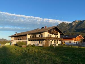 a large house in a field with mountains in the background at Hacklhof in Wallgau