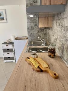 a kitchen counter with a wooden cutting board with cheese at Apartment Amalia Volosko in Opatija