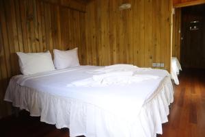 a large white bed in a room with wooden walls at Tree Houses Hotel in Fethiye