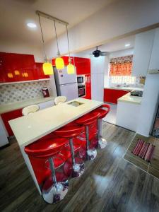 una cocina con armarios rojos y una barra con taburetes rojos en 3 Bedrooms with Pool Hanan Residence Ketumbar Heights Condominium en Cheras