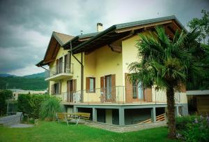 a yellow house with a balcony and a palm tree at Countryhouse Verso in Rovereto