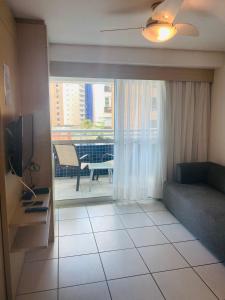 a living room with a couch and a table and a window at Beach Class Fortaleza by AM in Fortaleza